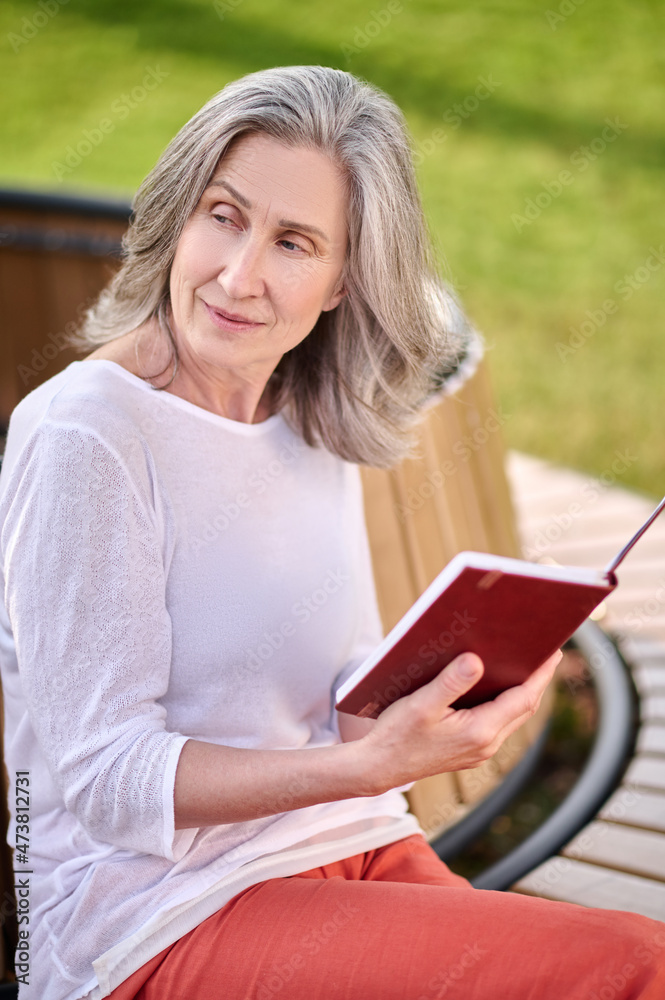 Obraz premium Meditative woman with book sitting on bench