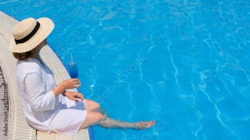 Senior woman relaxing in the hotel swimming pool. People are enjoying their summer vacation. All inclusive