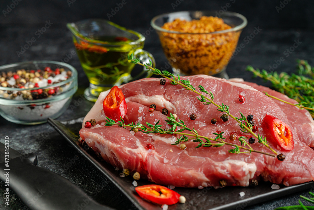 Pork steak on black slate plate with spices and herbs. Close up. Pork steak on black slate plate with spices and herbs. Close up.