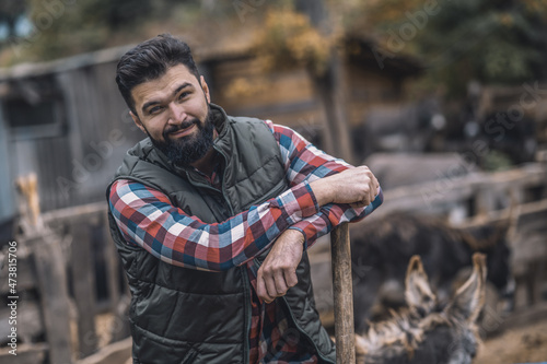 Dark-haired man resting after cleaning the cattle-pen