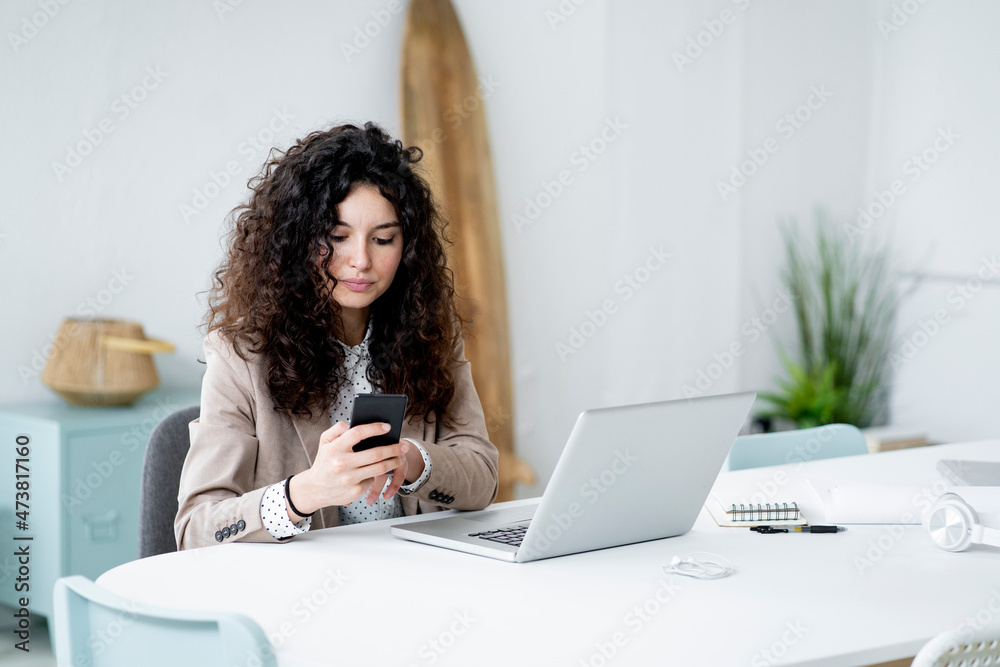 Businesswoman using mobile phone while working in office Businesswoman using mobile phone while working in office
