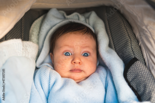 Surprised baby boy lying in pram
