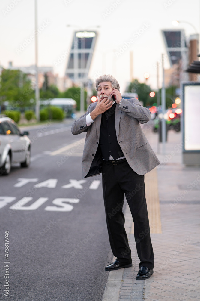 Businessman talking on mobile phone while hailing taxi at sidewalk Businessman talking on mobile phone while hailing taxi at sidewalk