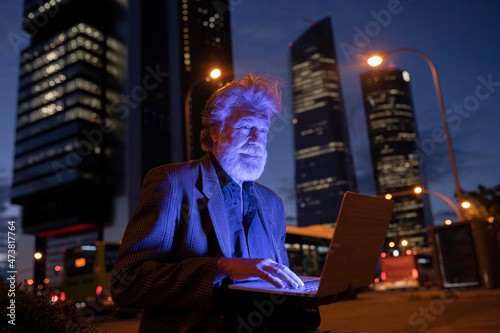 Male professional using laptop in city at night photo