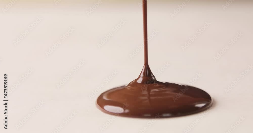 Melted chocolate syrup is pouring on a white background. Isolated. Making homemade cookies. Home confectionery.