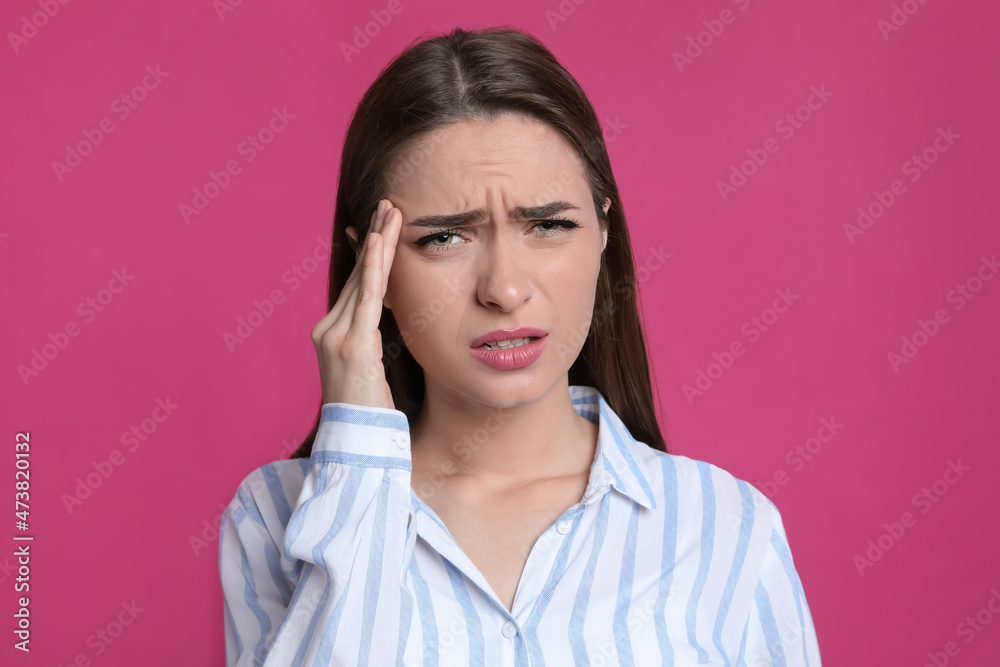 Young woman suffering from headache on pink background Young woman suffering from headache on pink background