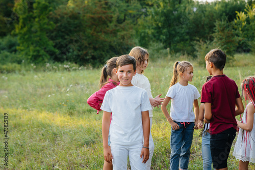 A group of happy children run and play in the Park during sunset. Summer children's camp © Andrii
