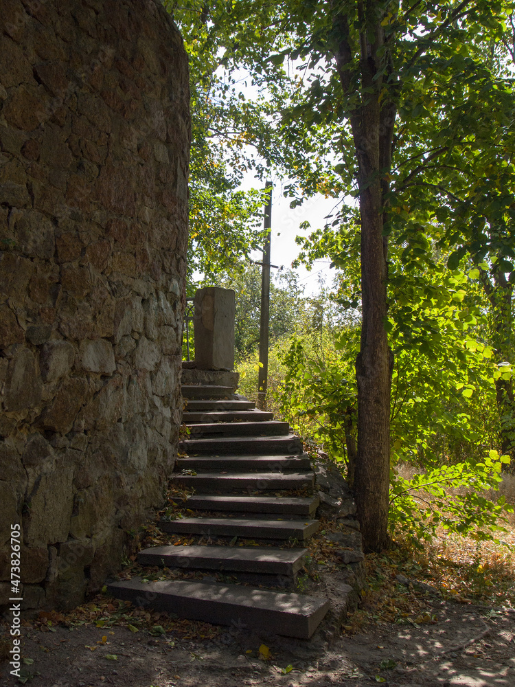 A circular staircase around an old stone wall. Walk in the park on a warm sunny autumn day.