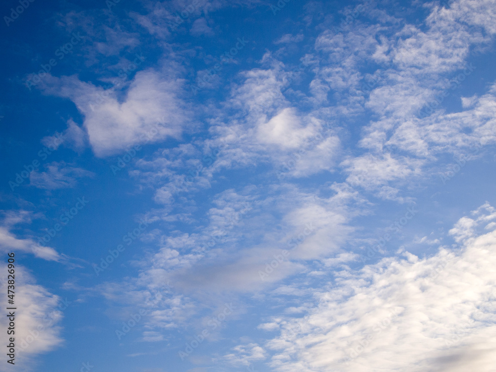 Bottom view of a bright blue sky with white and gray clouds. Sunny day. Abstract background.