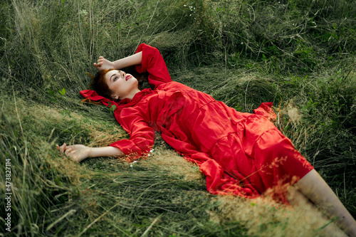woman in red dress lies on the grass in the field nature landscape © VICHIZH