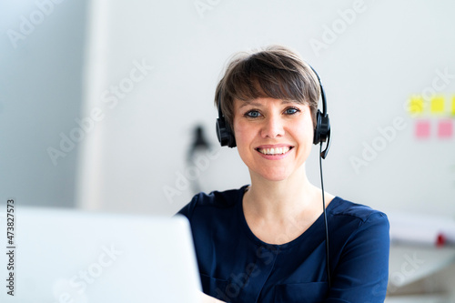 Smiling female professional with short hair wearing headset in office