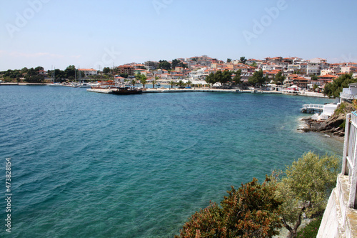 Sunny day in the seaside town. Clear sky, small waves at sea. White houses with red roofs. Coastline of the sea.