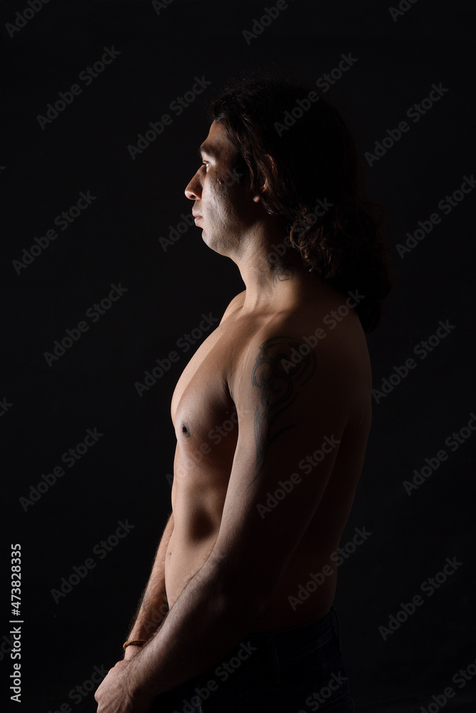 Naklejka premium side view of a man portrait of a low key man looking down on black background