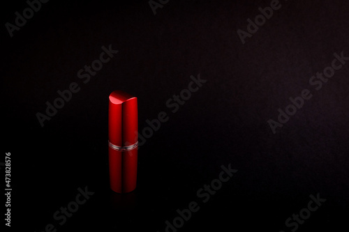 Red bottle with gold lipstick border on black background side view