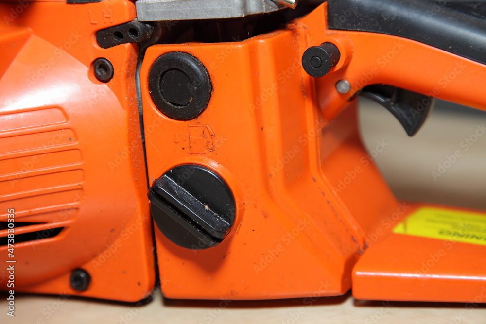 Orange chain saw fuel filling cap closeup - forestry tool equipment refueling maintenance Orange chain saw fuel filling cap closeup - forestry tool equipment refueling maintenance