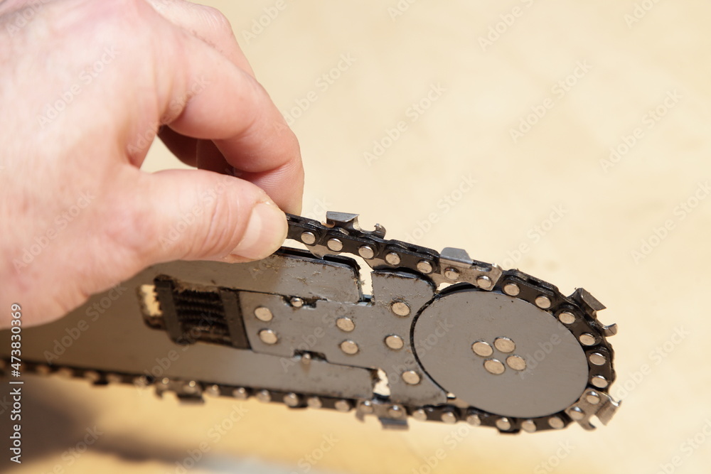 A man's hand holding the chain saw on chainsaw blade closeup, checking