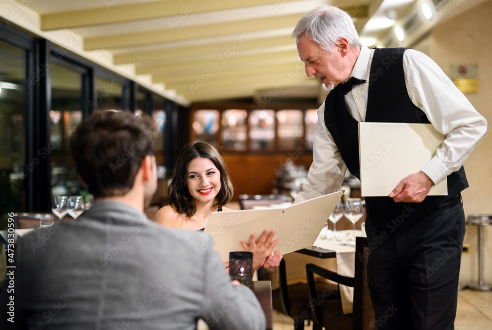 Waiter giving a menu to a couple in an elegant restaurant Waiter giving a menu to a couple in an elegant restaurant