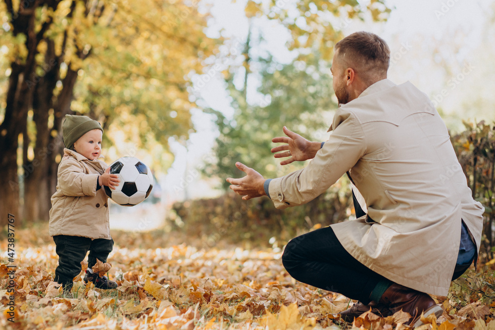 Fototapeta premium Father woth his little son in autumnal park playing with ball