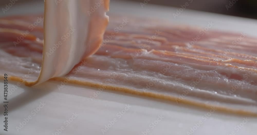 Chef tooks thin slices of smoked bacon in slow motion. Cooking with natural meat products, 4k 60p Prores