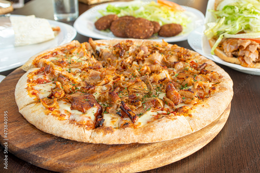 Freshly made pizza with ingredients and kebab meat or shawarma with cheese and cooked in a stone oven Freshly made pizza with ingredients and kebab meat or shawarma with cheese and cooked in a stone oven