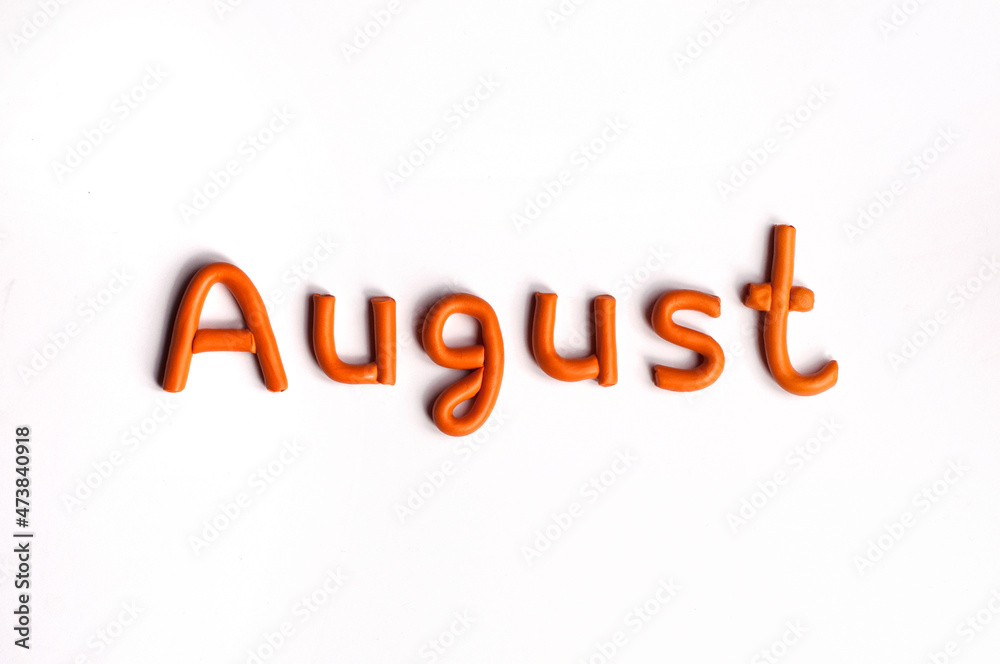 The word August is made of orange plasticine on a white background