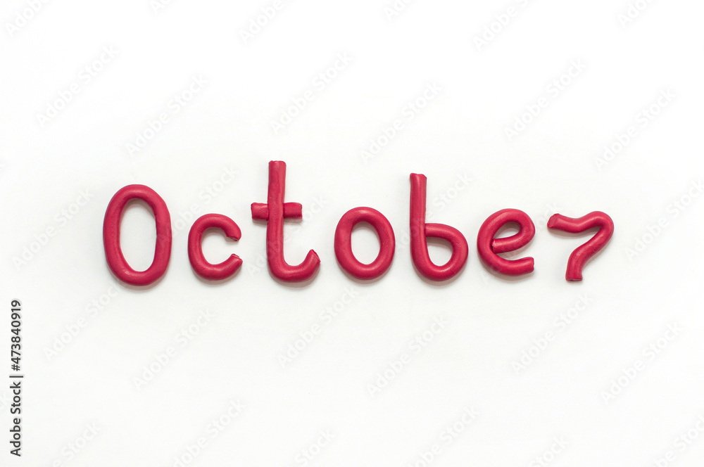 The word October is made of red plasticine on a white background