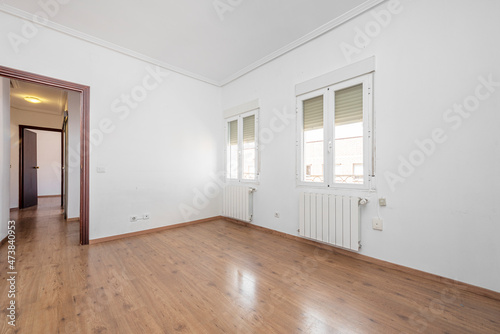 Unfurnished living room with white aluminum windows  chestnut wood flooring and aluminum radiators