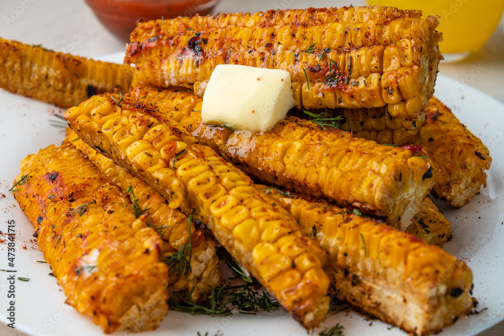 Grilled corn with paprika, pepper and garlic with a slice of melted butter. Close-up. Selective focus. Corn ribs.