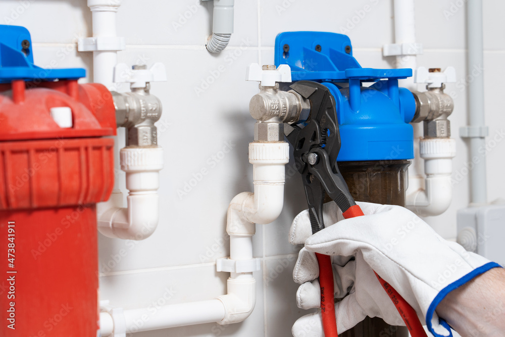 Man in glove repairs water pipe with wrench. Man in glove repairs water pipe with wrench.