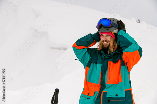 smiling man skier in bright colorful ski suit against background of snow