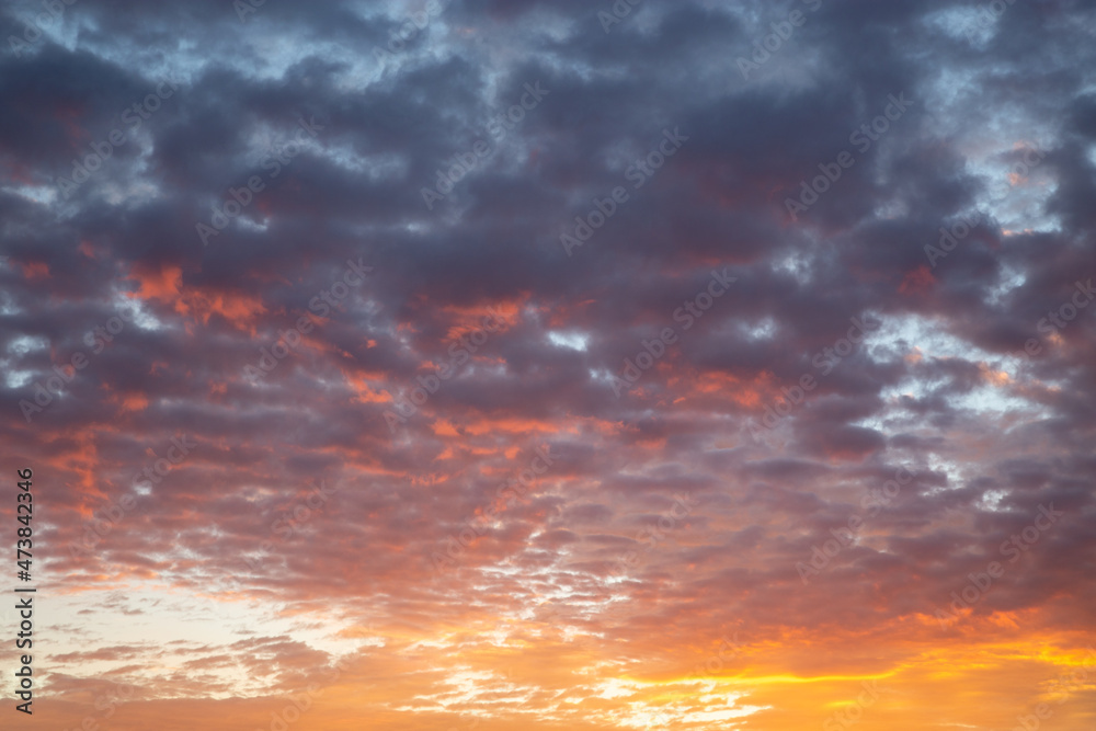 dramatic idyllic orange sky at dawn with dense, gray clouds