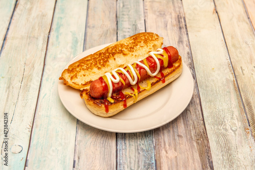 Classic hot dog with mustard, ketchup and mayonnaise on toasted brioche bread