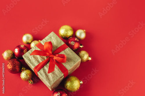 Gift box with red and golden balls on a red background. Holiday concept.