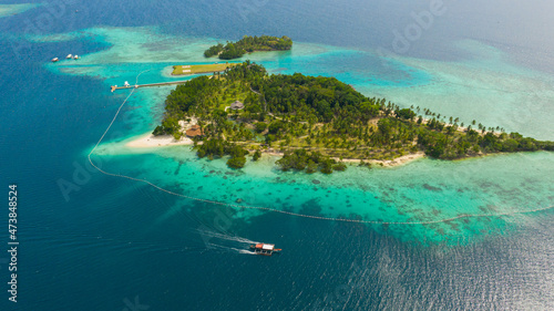 Malipano island with a sandy beach and azure water surrounded by a coral reef and an atoll, aerial view. Philippines, Samal.