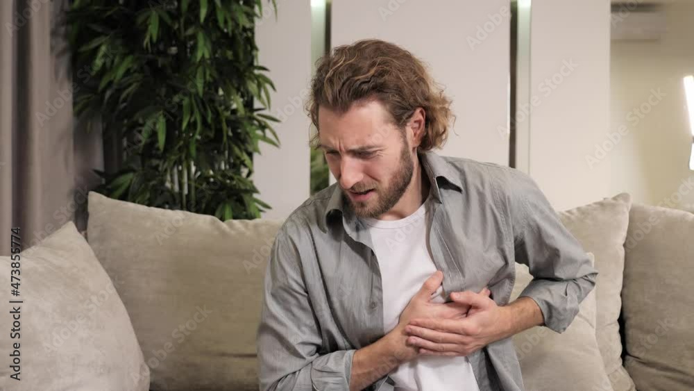 Heart Trouble breathing, chest pain, Asian man sitting on couch at home
