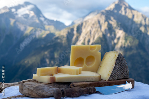 Cheese collection, French beaufort, abondance, emmental, tomme de savoie cheeses served outdoor in Savoy region, with Alpine mountains peaks on background photo