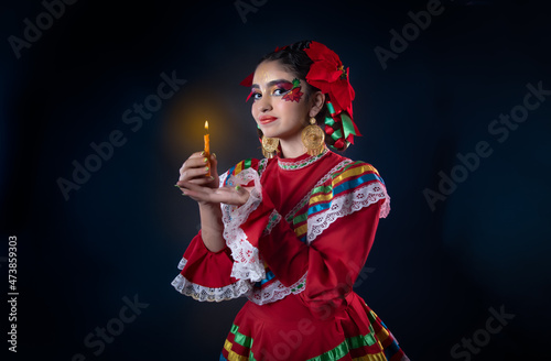 Mexican teenager with red dress and facial makeup rebozo and sparklers celebrating Mexican Christmas and traditional posada of the Mexican Christmas holidays