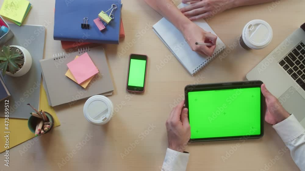 Business people using gadgets with chroma green screen top view. Creative workers discussing tasks. Project planning, group brainstorming. Team leaders working in modern office together.