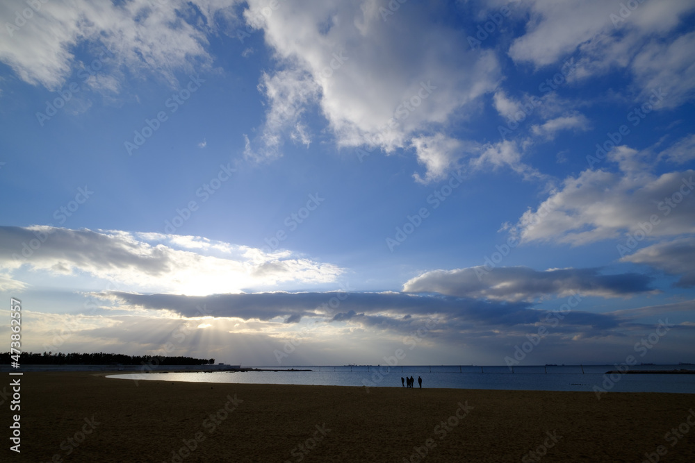 明け方の冬の海。太陽が昇り雲の間から顔を出し、水面はキラキラと輝く。兵庫県芦屋市芦屋浜で撮影。