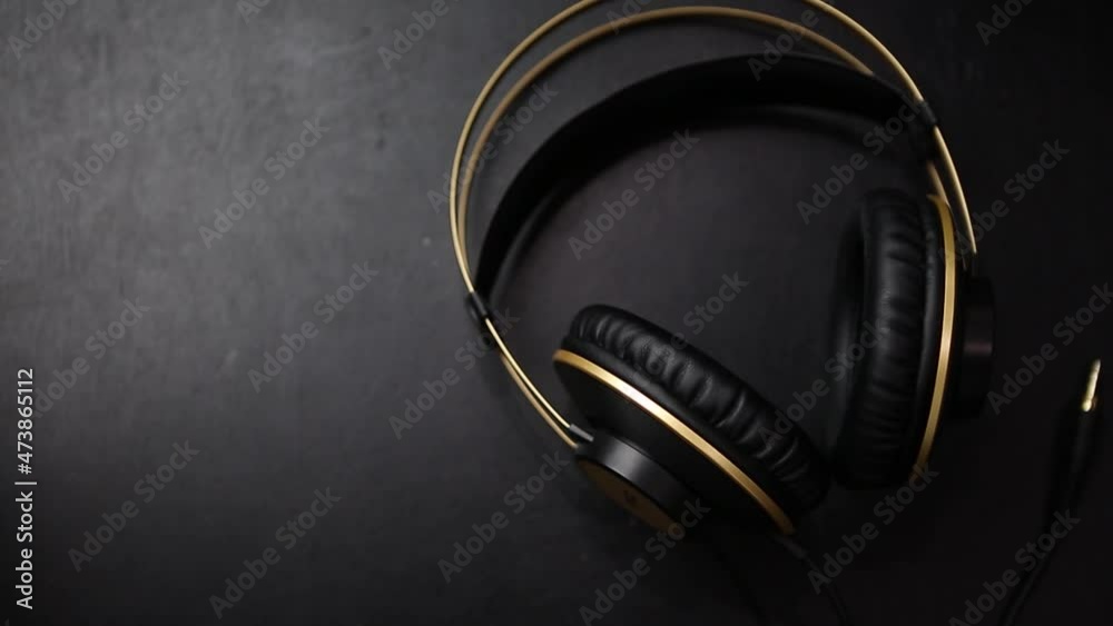 Professional hi fi headphones with wire filmed in flat lay style on table directly from above. Big black dj headset with powerful bass sound Professional hi fi headphones with wire filmed in flat lay style on table directly from above. Big black dj headset with powerful bass sound