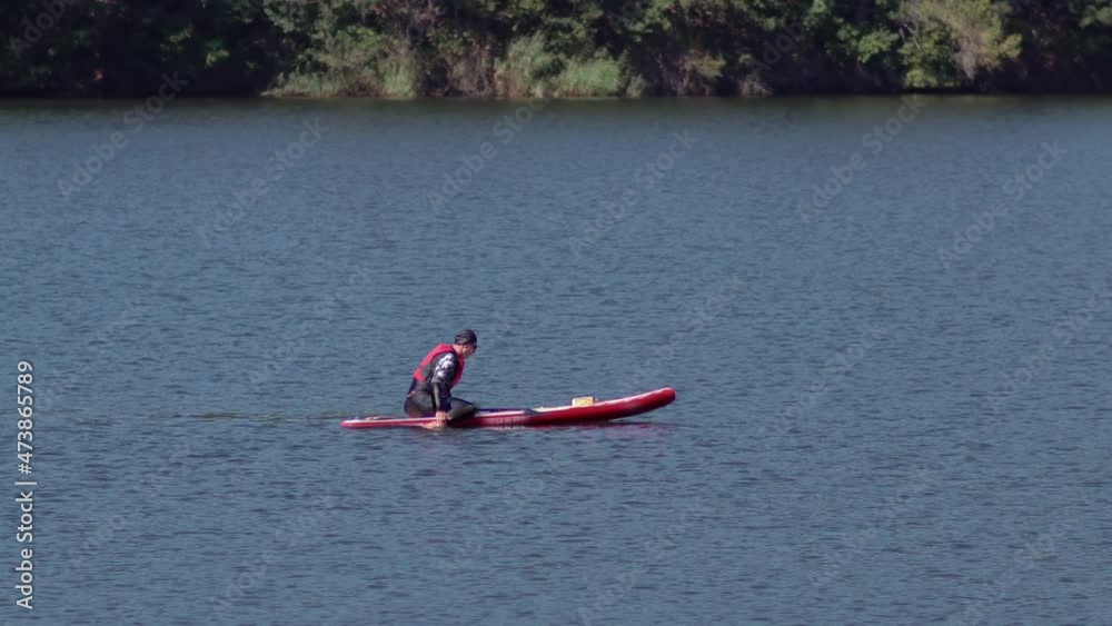 Stand up paddle board man paddle boarding on smooth lake surface standing happy on paddleboard. Summer holidays vacation travel.