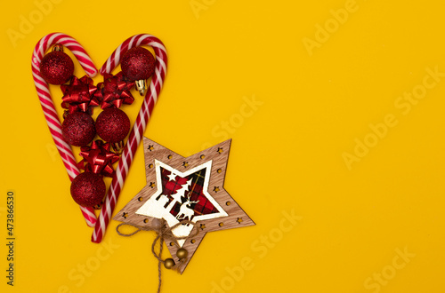 Fototapeta Naklejka Na Ścianę i Meble -  Christmass flatlay heart lined with Christmas lollipops and decorated with Christmas tree toys 