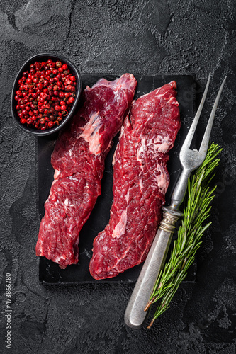 Raw Machete steak or hanging tender cut with herbs. Black background. Top view