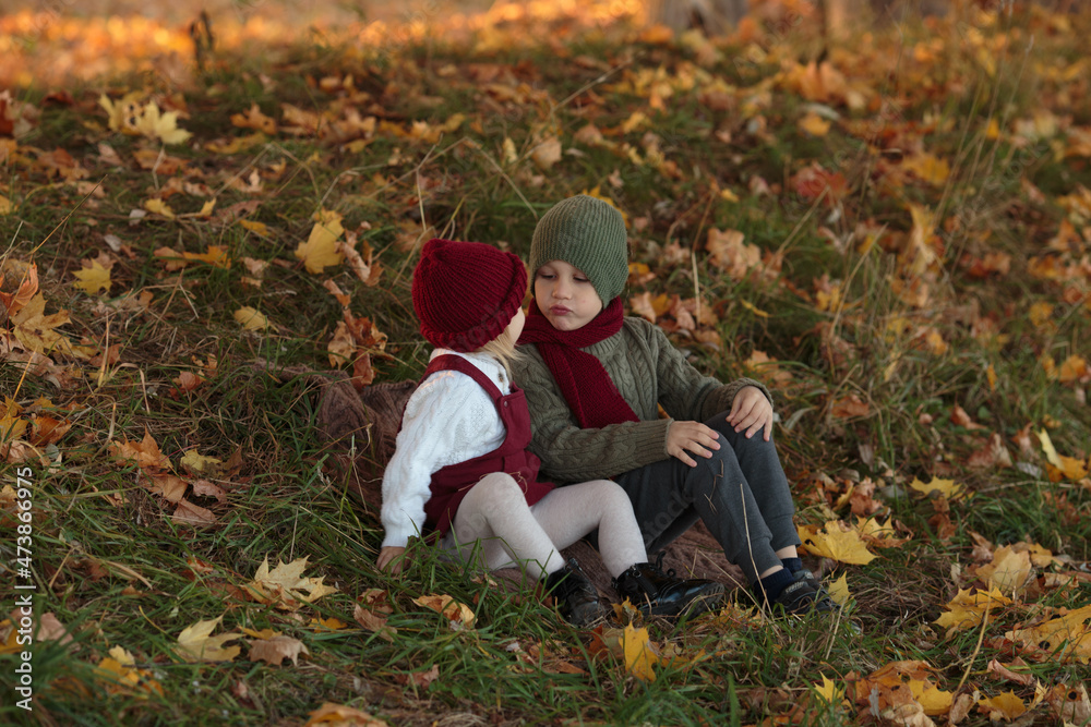 two children a boy and a girl are sitting on the ground and the boy reaches out to kiss the girl
two children a boy and a girl are sitting on the ground and the boy reaches out to kiss the girl
