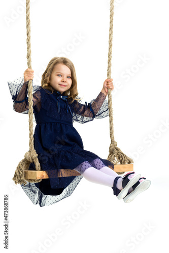 Lovely blonde little girl swinging on rope swing