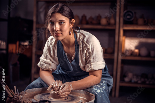Stylish female master works with clay on a potter's wheel. Restoration of forgotten pottery traditions.