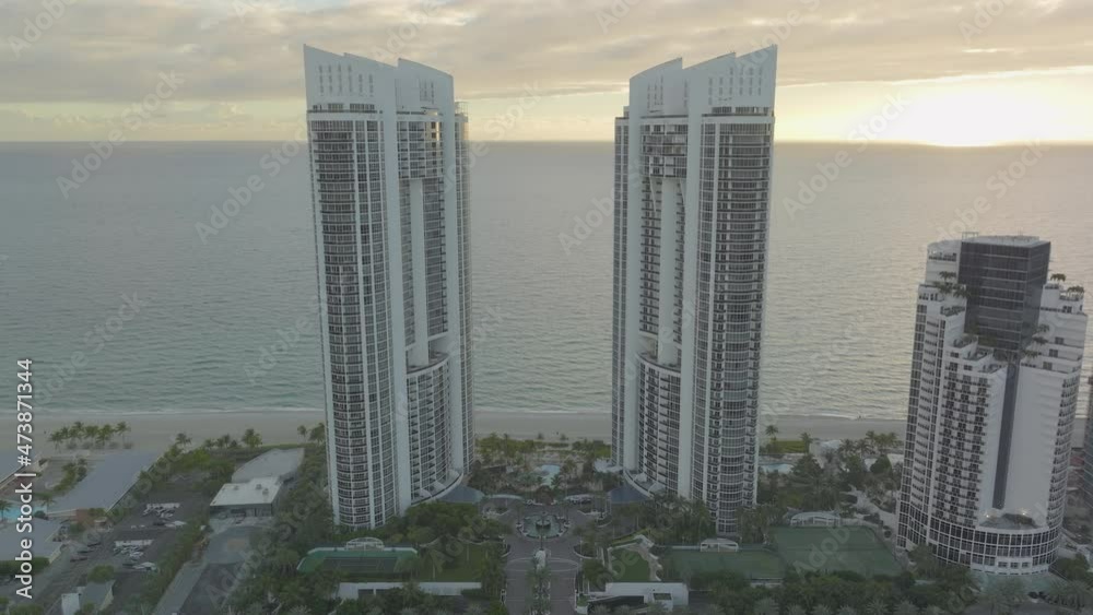 zoom out on two large buildings at the beach showing waves and ...
