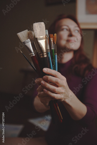 Young beautiful girl, the artist holds paintbrushes in her hands. 