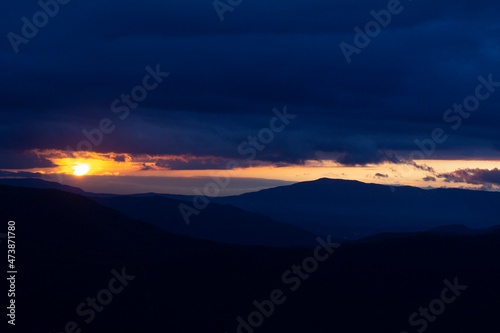 Beautiful orange color evening sunset with dark silhouette of alpes range mountains view 