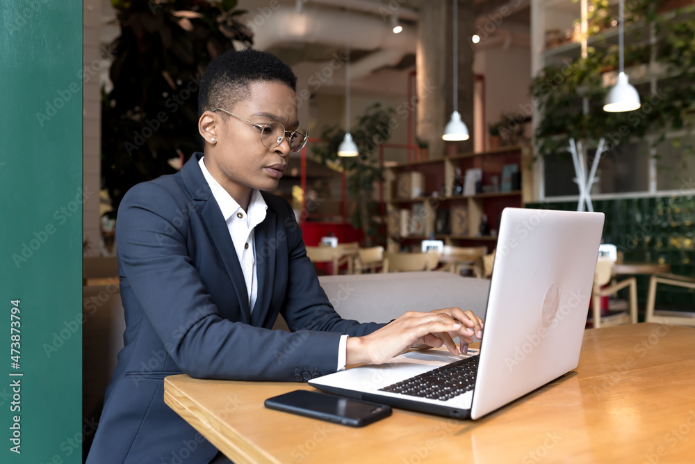 Young business woman working is a cafe with a laptop, African-American is focused on the end of the project, the deadline is for lunch break Young business woman working is a cafe with a laptop, African-American is focused on the end of the project, the deadline is for lunch break
